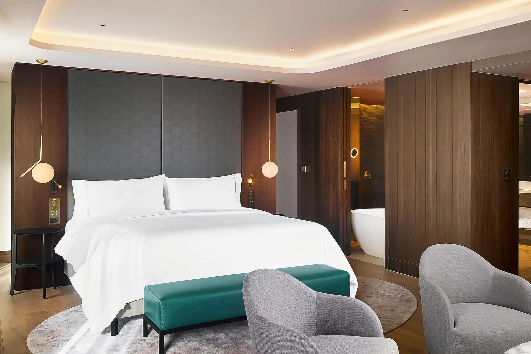 A modern hotel room with a bed and chairs.
